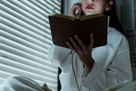Cropped image of a book in woman's hand while she read it at the window.