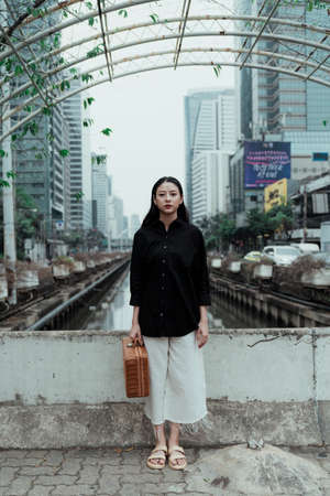 Full portrait shot of woman in black shirt standing on the bridge.