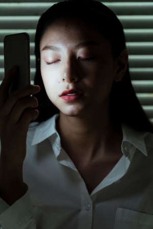 Long hair woman close her eyes while she light her face with flashlight.の写真素材