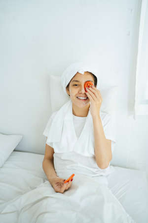 Woman with towel on head remove tomato from her eyes.の写真素材