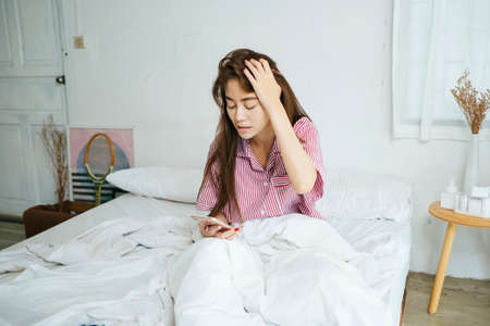 The message in smartphone depress long hair woman in the morning.の写真素材
