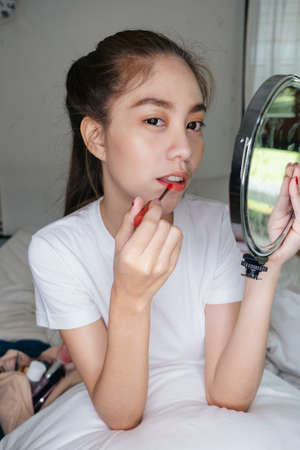 Ponytail woman show lipstick to the camera before apply on her lip while record the video.の写真素材