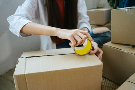 Cropped image of box will be closed with masking tape while long haie woman pack the goods as online order.の写真素材