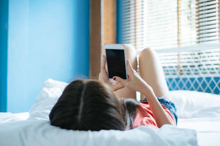 Long hair woman lie down on the bed in the morning and shopping online with her smartphone.