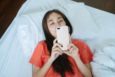 Long hair woman lie down on the bed in the morning and shopping online with her smartphone.