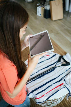 Long hair woman take a photo of the stripped shirt, her goods, then send the photo to the customer...