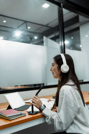 Black long hair podcaster girl in white shirt wearing white headphone telling the fun story while...