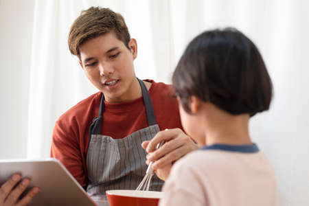 Asian family cooking activity - Father searching on internet how to cooking with son.
