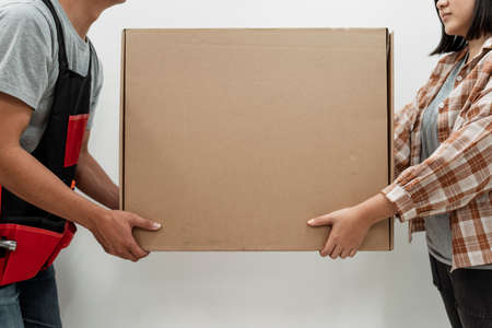 Man and woman moving a big box together. Copy space in the middle.の写真素材