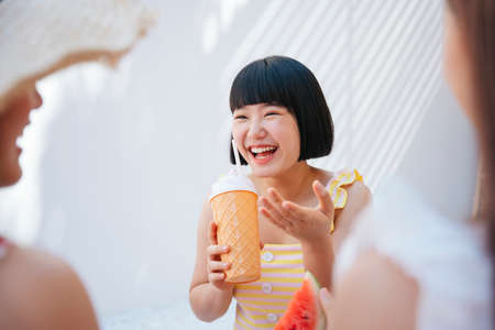 Bob hairstyle cute asian woman talking with friend while drinking juice from plastic bottle.