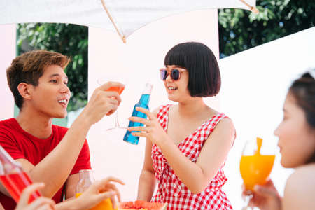 Three asian people enjoy beverage drinks in summer party outdoors.