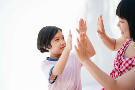 Sister making high five with little brother to cheer him up.の写真素材