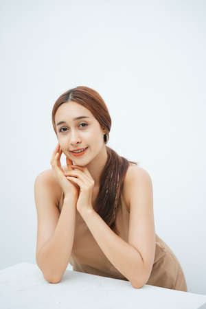 Close up portrait of attractive beautiful brunette woman isolated over white background. Touching soft cheek and smile. Cosmetic concept.の写真素材