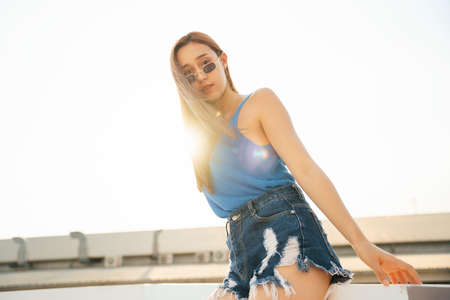 Portrait of beautiful sexy woman on tank top blue vest shirt wearing sunglasses. Sexy woman with...