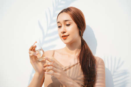Attractive beautiful brunette woman holding cosmetic bottle product. Natural product. Cosmetic concept.の写真素材