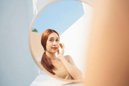 Attractive beautiful brunette woman applying cosmetic in front of the mirror. Cosmetic concept.の写真素材