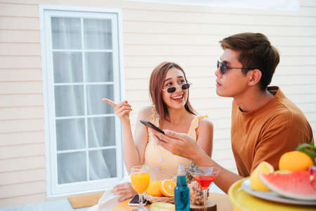 Cheerful couple enjoy having good time in summer at tropical bar on vacation.の写真素材