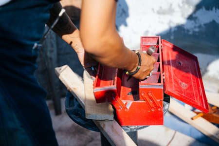 Cropped image of red toolbox in a man hand whle holding after finish his work, keep the tools in the...