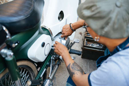 The mechanic fixing the motorbike, motorcycle, at his home by himself, use the tools from toolbox.の写真素材