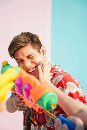 Local thai man playing water gun in Songkran festival in Thailand. Man got pat by wet powder on his face.の写真素材