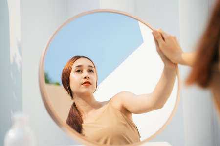 Attractive beautiful brunette woman applying cosmetic in front of the mirror. Cosmetic concept.の写真素材
