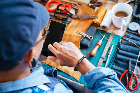 Top view of a man in blue shirt while he. sitting at the table and do his work, look at the...