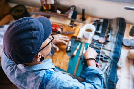 Top view of a man in blue shirt while he. sitting at the table and do his work.