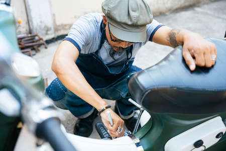 The mechanic fixing the motorbike, motorcycle, at his home by himself.の写真素材