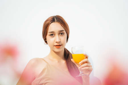 Attractive beautiful brunette woman enjoy drinking orange juice in glass cup isolated on white background.の写真素材
