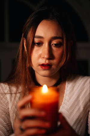 Close up portrait - Beautiful woman with scent perfume candles in the dark room.の写真素材