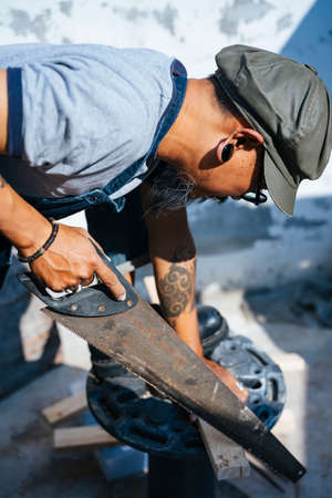 Craftsman sawing the plank on the woodbench to cut it.の写真素材