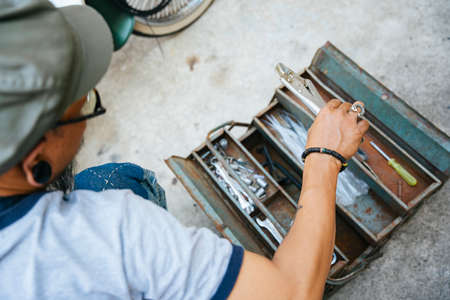 The mechanic fixing the motorbike, motorcycle, at his home by himself, use the tools from toolbox.の写真素材