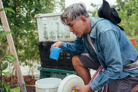 Asian elderly senior farmer taking a break drinking water from bucket.の写真素材
