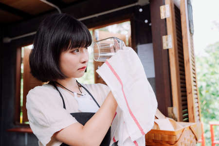 Beautiful asian thai woman clean up a wine glass. Local business shop.