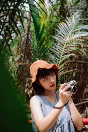 Young asian Thai woman traveler with vintage camera at country side road. Local trip.