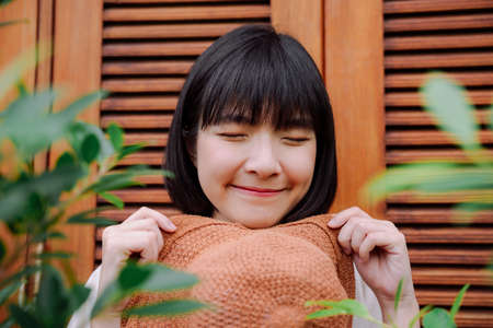 Close up - Beautiful asian thai woman with a hat over wooden door background.