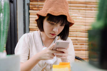 Beautiful asian thai woman taking picture of a cake before eating. Camera eat first.の写真素材