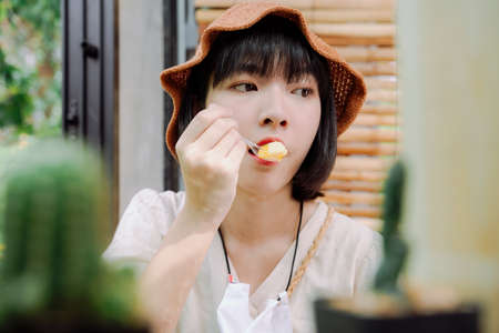 Close up - Beautiful asian thai woman enjoy eating dessert cake with spoon. Local dessert.の写真素材