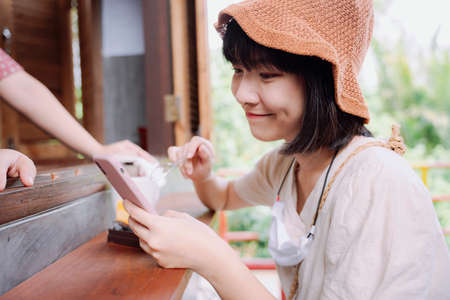 Beautiful asian thai woman enjoy eating cake and using smartphone to tell people how delicious this cake is.の写真素材