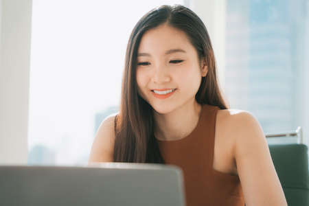 Cheerful Beautiful asian thai businesswoman working on laptop at office building.の写真素材