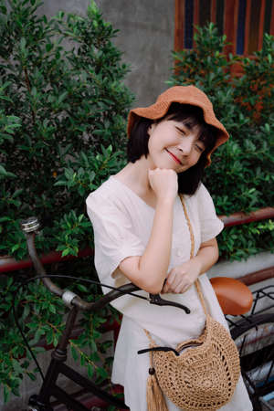Fashion portrait - Beautiful asian thai woman short dark hair wear hat posing on bicycle.の写真素材