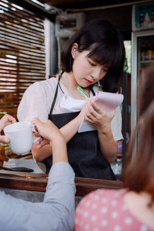 Beautiful asian thai woman coffee shop owner taking order from customer. Local shop. Local business woman.の写真素材