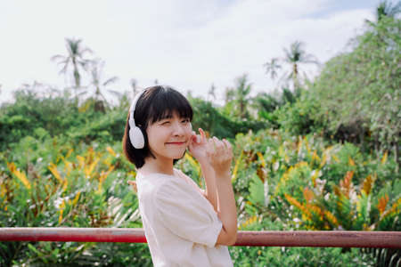 Beautiful asian thai woman short dark hair listen to music with wireless headphone in nature outdoors.の写真素材