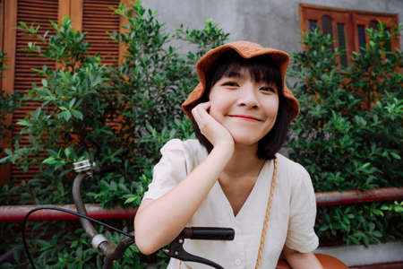 Fashion portrait - Beautiful asian thai woman short dark hair wear hat posing on bicycle.の写真素材