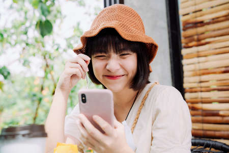 Beautiful asian thai woman taking selfie with smartphone and cake before eating. Social media blogger. Influencer. Food blogger or vlogger.の写真素材