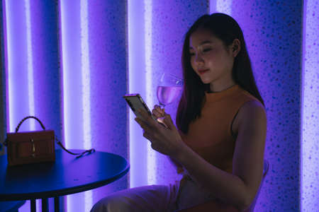 Beautiful asian thai woman using smartphone in night club.