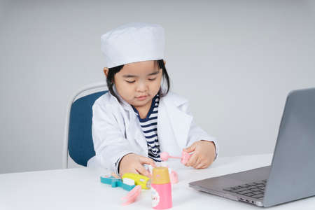 Pretty asian thai kid role play as a dentist at office room.