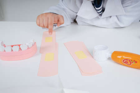 Pretty asian thai kid play role as doctor point out at bandage medial plaster on table.