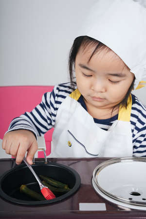 Pretty asian thai kid play role as a chef cooking food at stove station.の写真素材