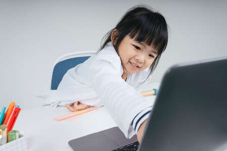 Pretty asian thai kid play role as a doctor point out at monitor screen at laptop computer.の写真素材